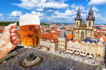 Poster Bière Hand with a mug of beer on the background of the Old Town Square in Prague