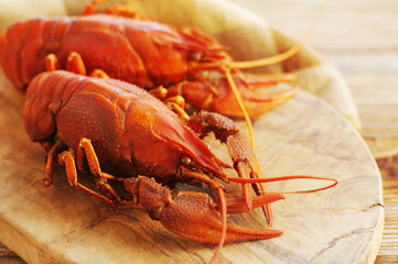 Boiled crayfishes on a wooden board on a wooden background, close up