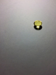 Minimalistic shot of fish oil capsule laying on paper background. Rule of thirds used.