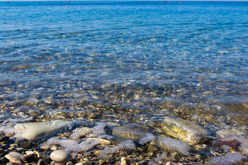 sea pebble beach with multicoloured stones, waves with foam