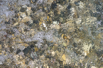 sea pebble beach with multicoloured stones, waves with foam