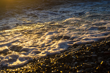 sea pebble beach with multicoloured stones, waves with foam