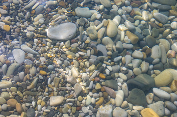 sea pebble beach with multicoloured stones, waves with foam