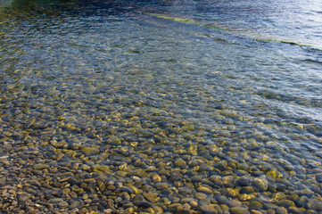 sea pebble beach with multicoloured stones, waves with foam