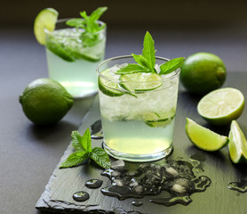 Cold cocktail with lemon liqueur, lime, tonic, ice on dark background.