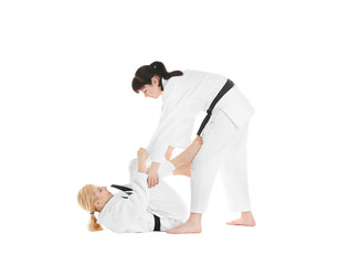 Young sporty women practicing martial arts on white background