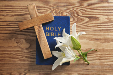 Wooden cross, Holy Bible and white lily on table