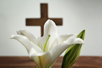White lily and blurred wooden cross on background
