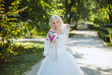 Fototapeta na wymiar Счастливая невеста на прогулке в зеленом парке