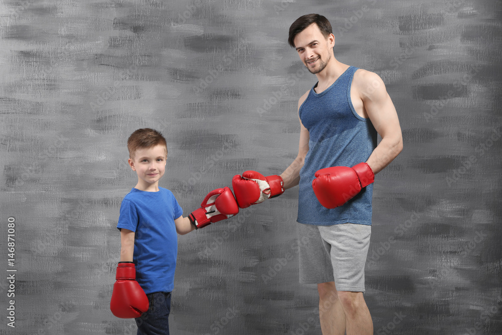 Wall mural father and son during boxing training near color wall