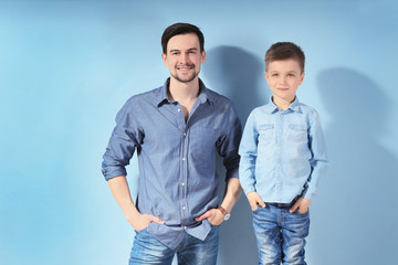 Handsome man and his son on color background