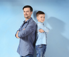 Handsome man and his son on color background