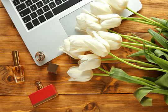 Composition of flowers and computer on wooden table