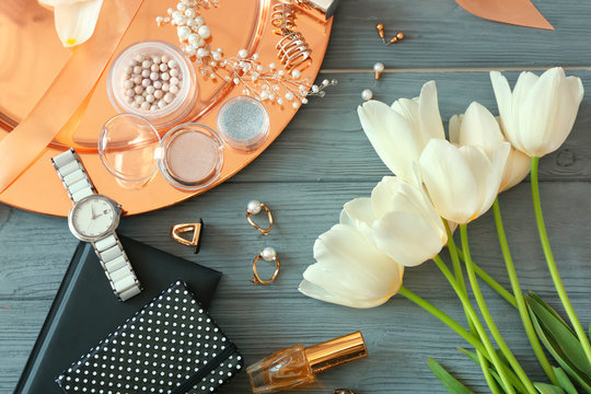 Composition of flowers, accessories and cosmetics on wooden table