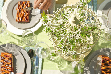 Decorative cage with blooming branch on served table