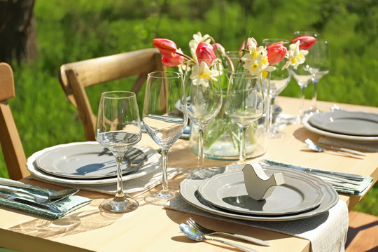 Beautiful table setting with vase of flowers in garden