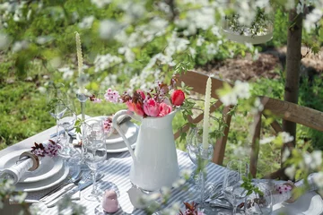 Crédence de cuisine en verre imprimé Pique-nique Jug with blooming bouquet of flowers on served table in garden