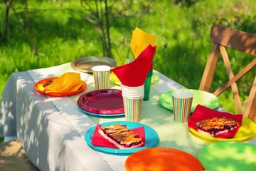 Selbstklebende Fototapeten Tisch serviert mit Einweggeschirr im Garten © Africa Studio