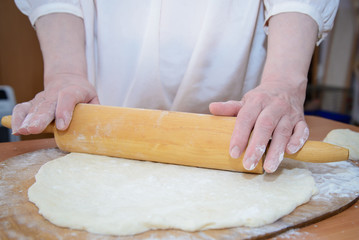 Female hands rolling dough closeup