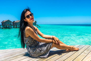 Portrait of happy young woman at beautiful water villa at Maldives island. Travel and Vacation. Outdoor shot.