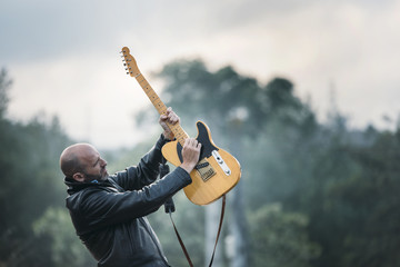 Man with electric  guitar in the field