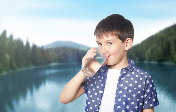 Little boy with glass of clean water on landscape background