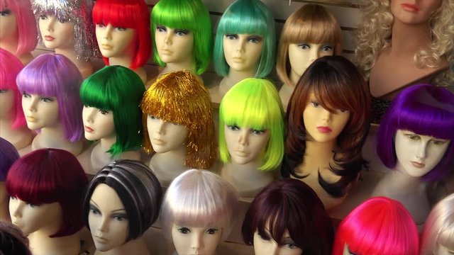 Mannequins wearing colorful wigs in a wig shop store window