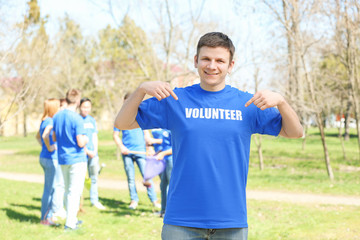 Handsome young volunteer with team outdoors