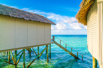 Beautiful water villas in tropical Maldives island at the sunrise time .