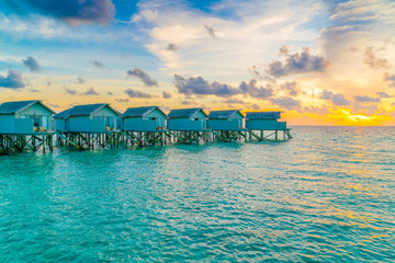 Beautiful water villas in tropical Maldives island at the sunset time .