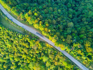 Aerial shot with a drone of a tropical rain forest and a rural road in Thailand .