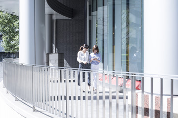 Two female office workers are walking outside on a sunny day