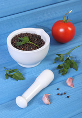 Black pepper in mortar and vegetables on blue boards