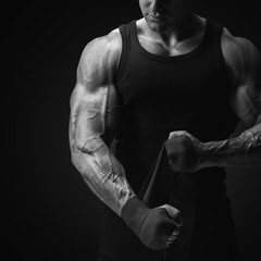Croped shot of strong man wrap hands on black background Man is wrapping hands with boxing wraps...