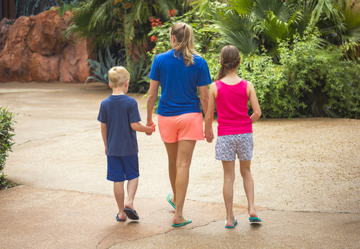 View From Behind Of A Cute Family Holding Hands Together