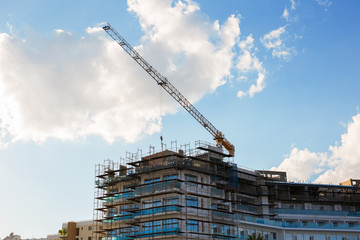 Building crane and building under construction against blue sky