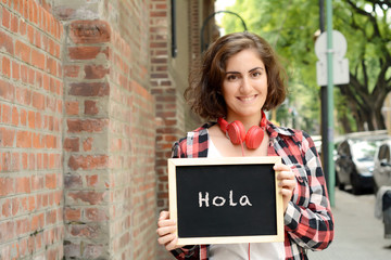 Woman holding chalkboard with "hola". © Mego-studio
