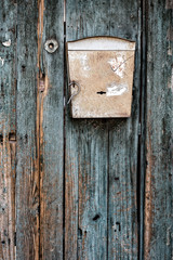 An old mailbox on green painted wooden door.