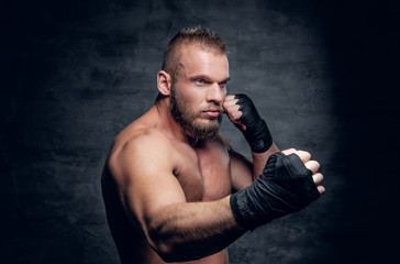 Fototapeta na wymiar Studio portrait of brutal bearded fighter over dark grey background.
