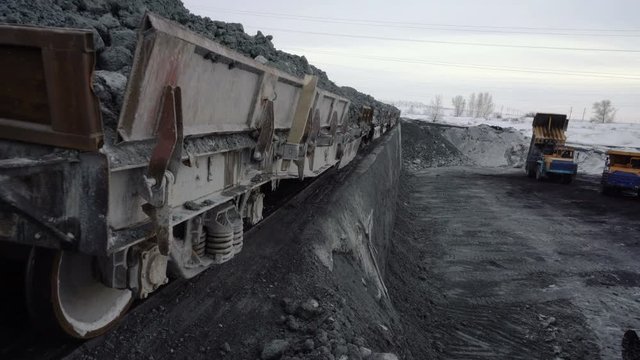 Tilt up tracking shot of freight train with copper ore arriving at the unloading platform.
