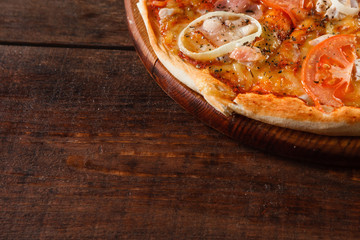 Italian national fast food background. Appetizing fresh pizza with tomato, cheese, onion and ham served on wooden rustic table with free space for text.