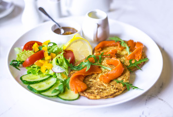 Potato pancakes with sauce. Vegetable fritters. Latkes on white plate, served with salt salmon.