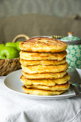 Stack of golden delicious homemade cottage cheese fritters or pancakes on white plate, rural kitchen interior, cozy atmosphere