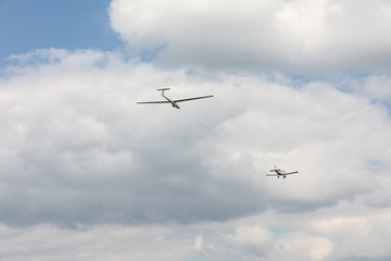 Glider towed on a rope flying on a blue sky background.