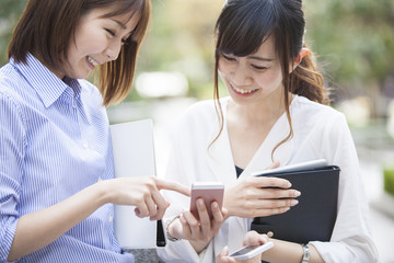 Women are smiling while watching smartphone