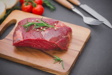 Raw beef on a cutting board  with spices and ingredients for cooking.