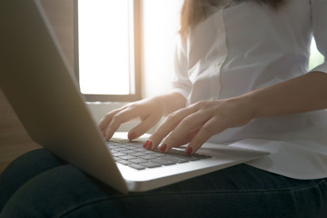 Close-up image of young woman hands typing and writing massages on laptop,working on cafe ot home.