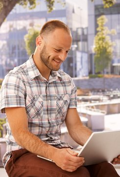 Happy man with laptop outdoors