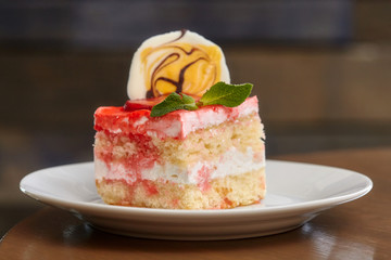 Piece of cake with strawberry and jam on white dish