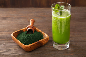 Green smoothie with spirulina on wood background